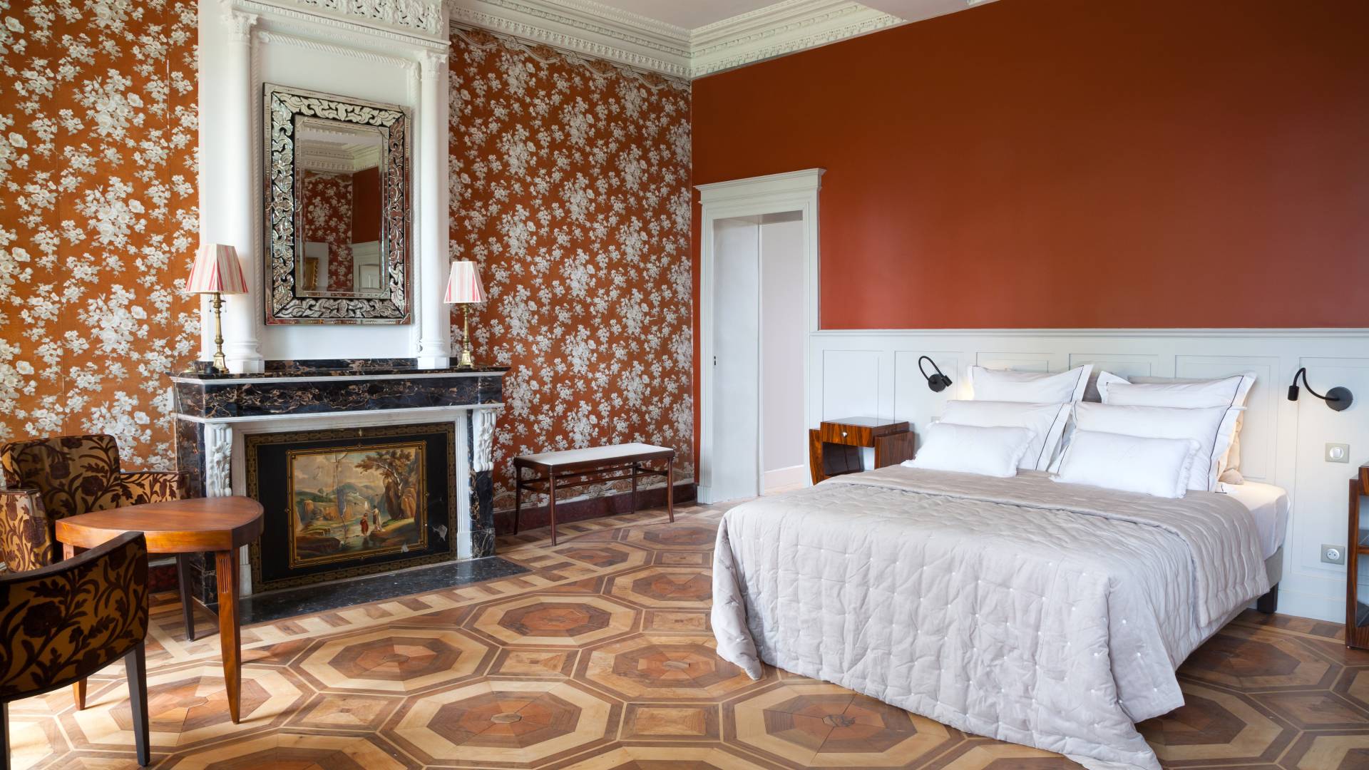 A bedroom decorated with varying patterns of burnt orange designs on the walls and floor with white, vintage crown molding.