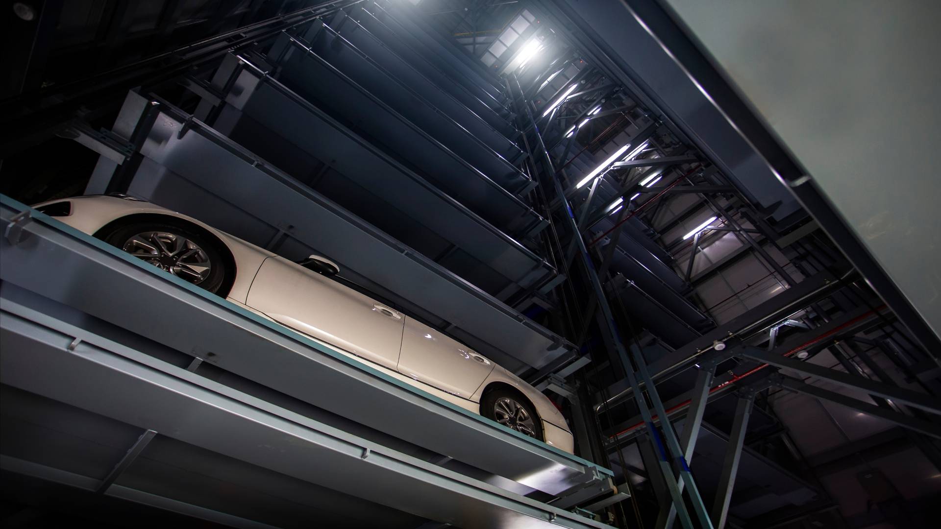 Inside an automated car parking system that is built vertically, and there’s a close-up of a white car that's parked.