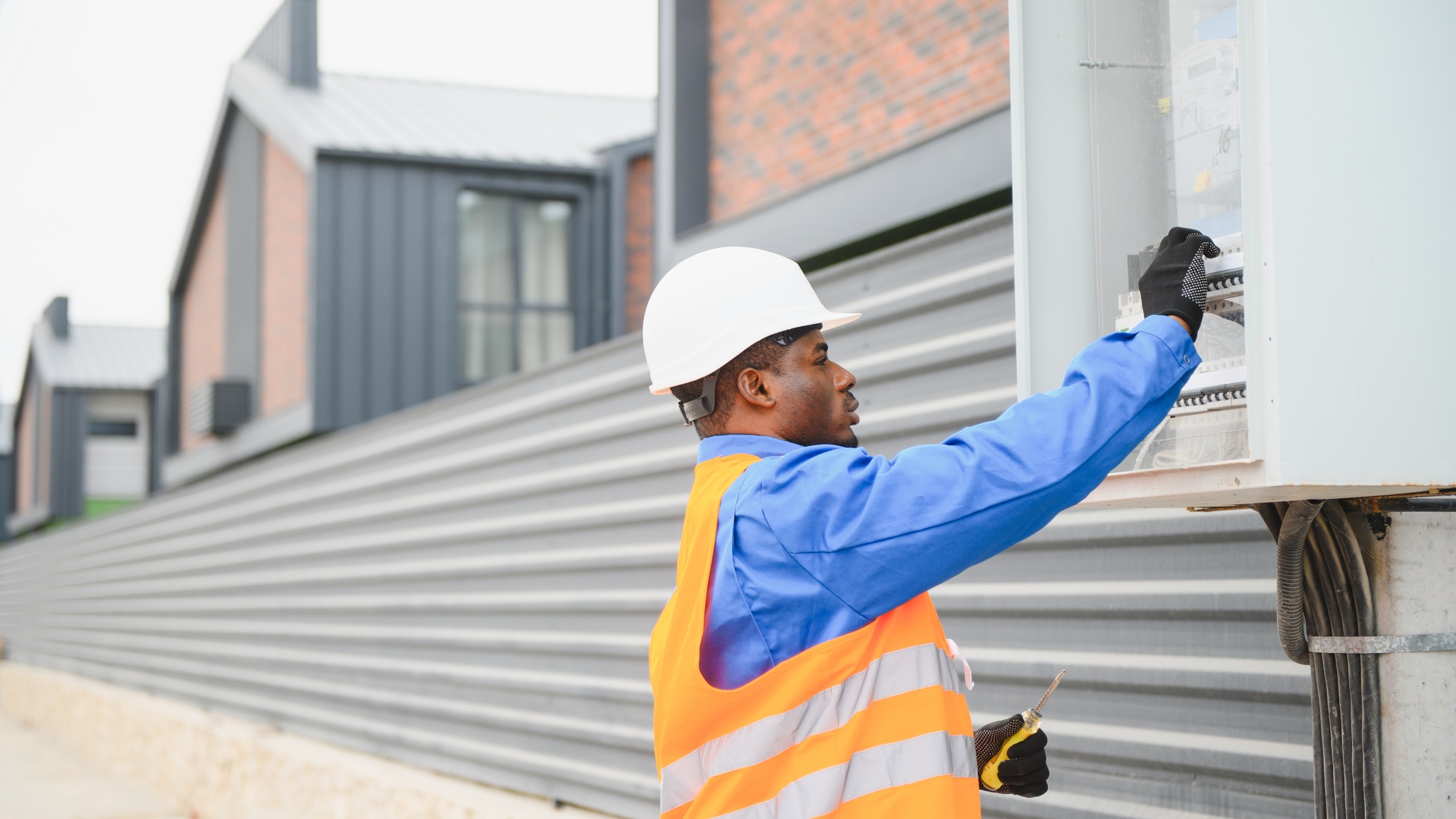An electrical engineer examining the power distribution system. He is wearing a hard hat and a safety vest.