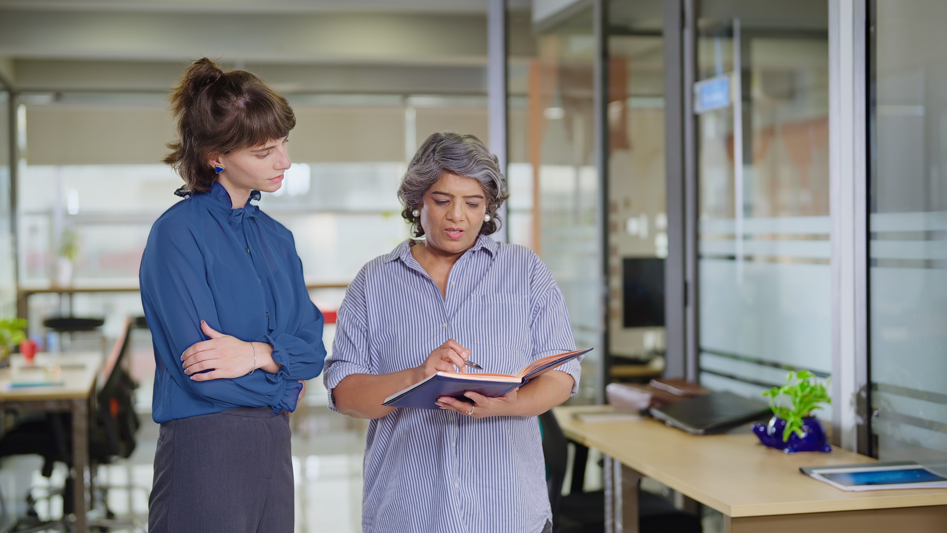 A young adult is talking to a mature woman about finances. The young woman is focused on what the mature lady is saying.