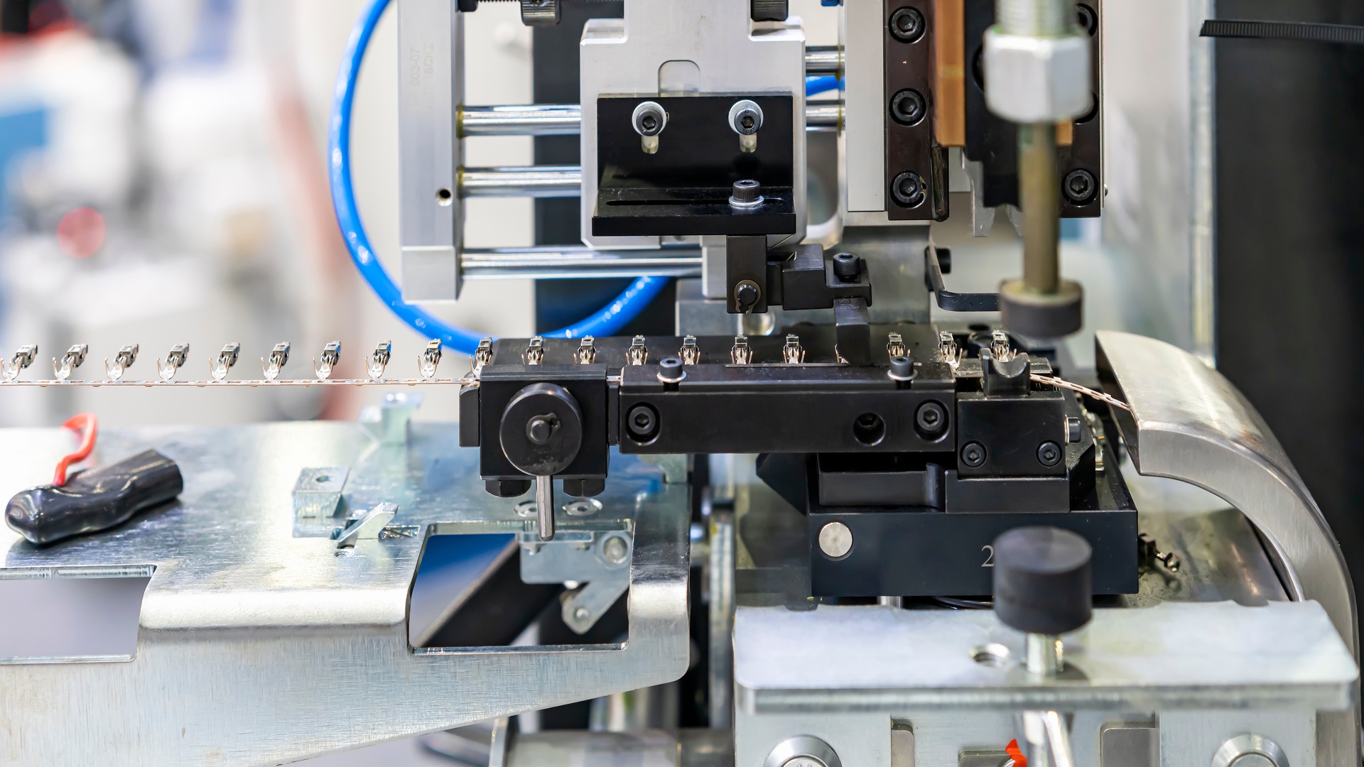 A full view of an automatic electric terminal crimping machine with a conveyor belt for industrial electrical wiring.
