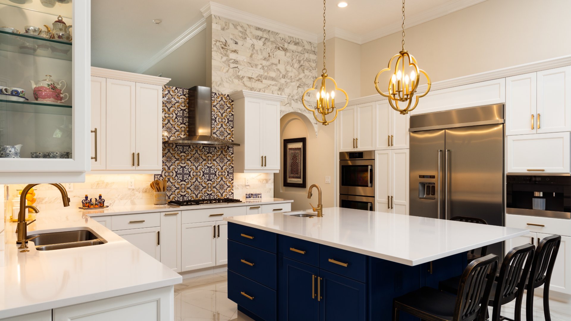 A residential kitchen with a chandelier hanging from the ceiling. There is a stove with a tiled backsplash.