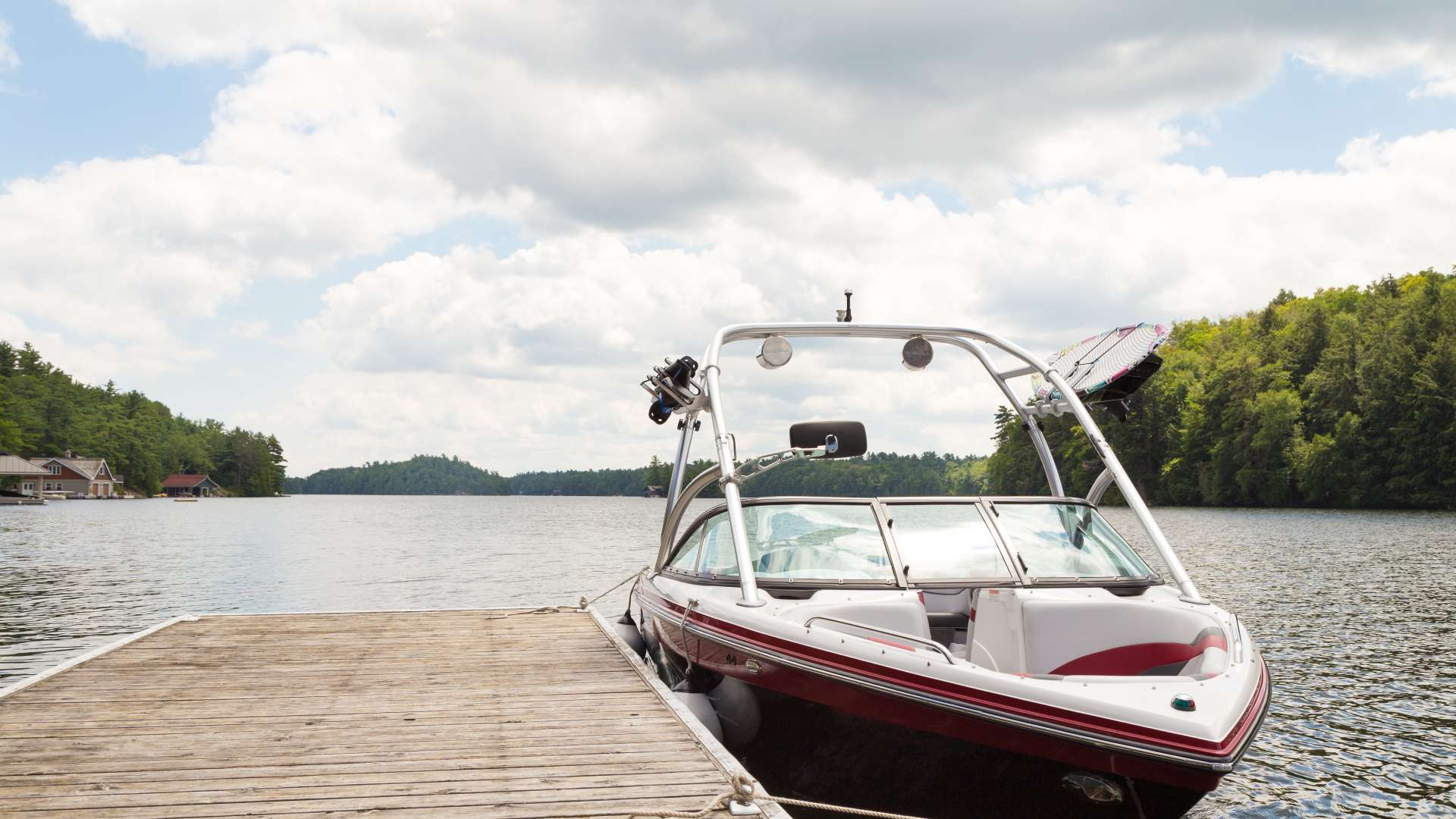 A black, red, and white boat sits in a large body of water. The boat is tied up to a large, tan dock.