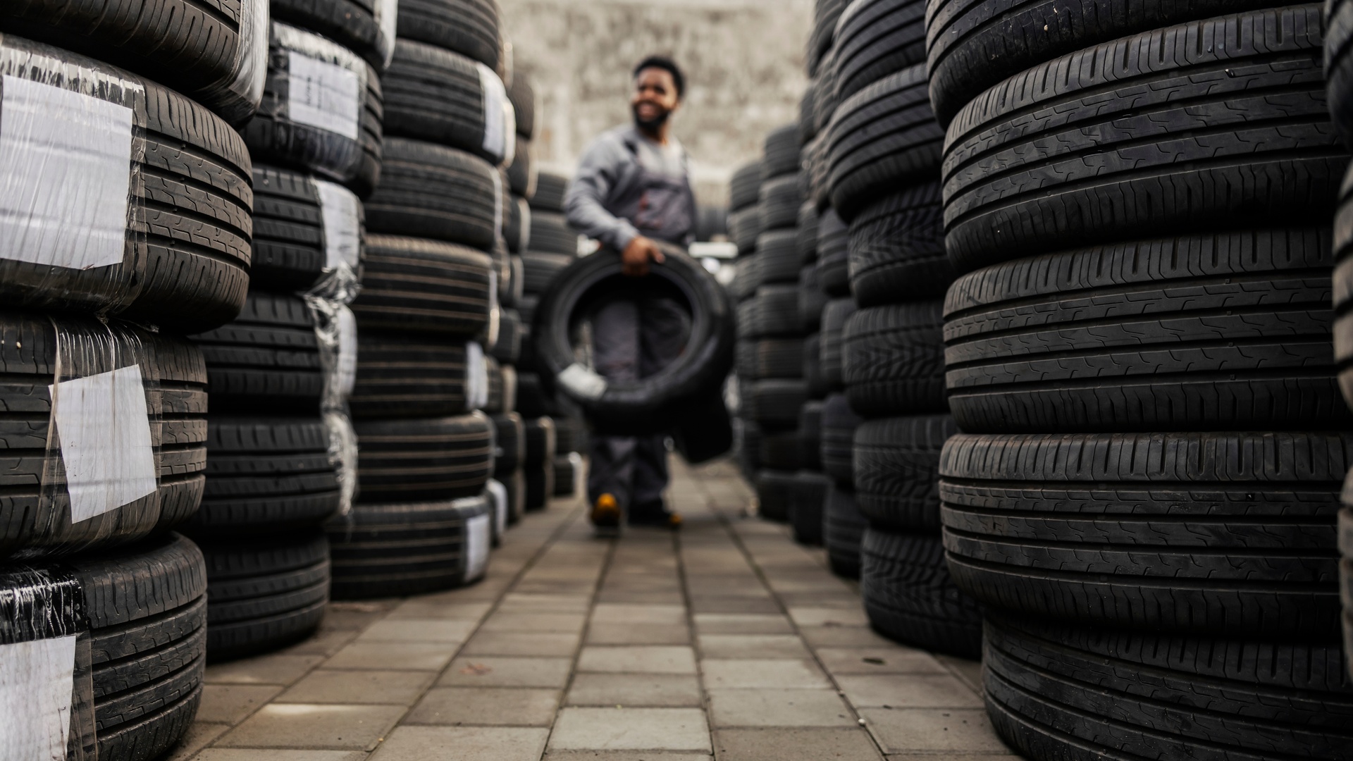 American-made tires stacked up creating an aisle in the center. Someone is at the end of the aisle holding one tire.