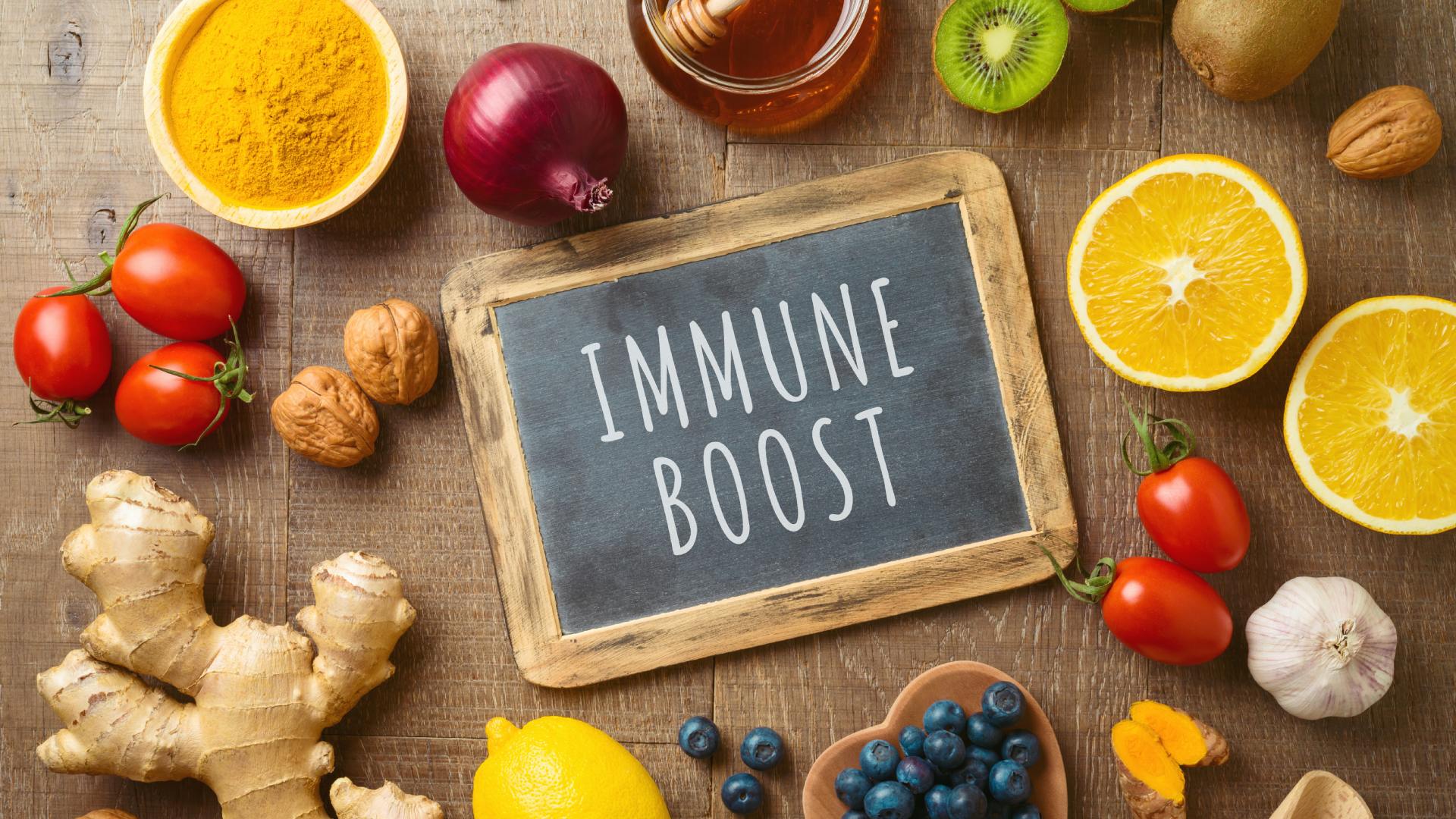 Immune-boosting foods like honey, citrus, tomatoes, and nuts, arranged around a chalkboard sign that reads "immune boost."