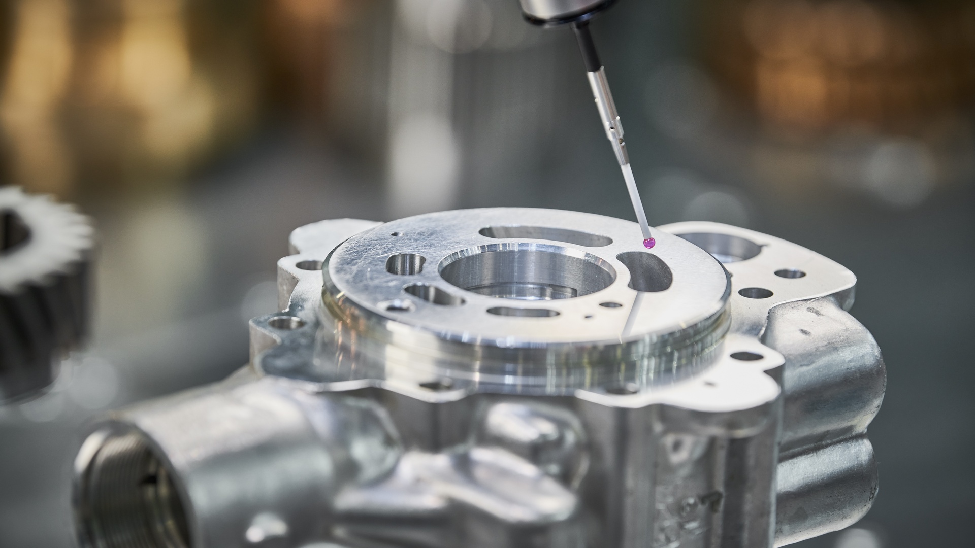A close-up of a CMM with a ruby-tipped stylus taking measurements of a part. The stylus is hovering over the part.