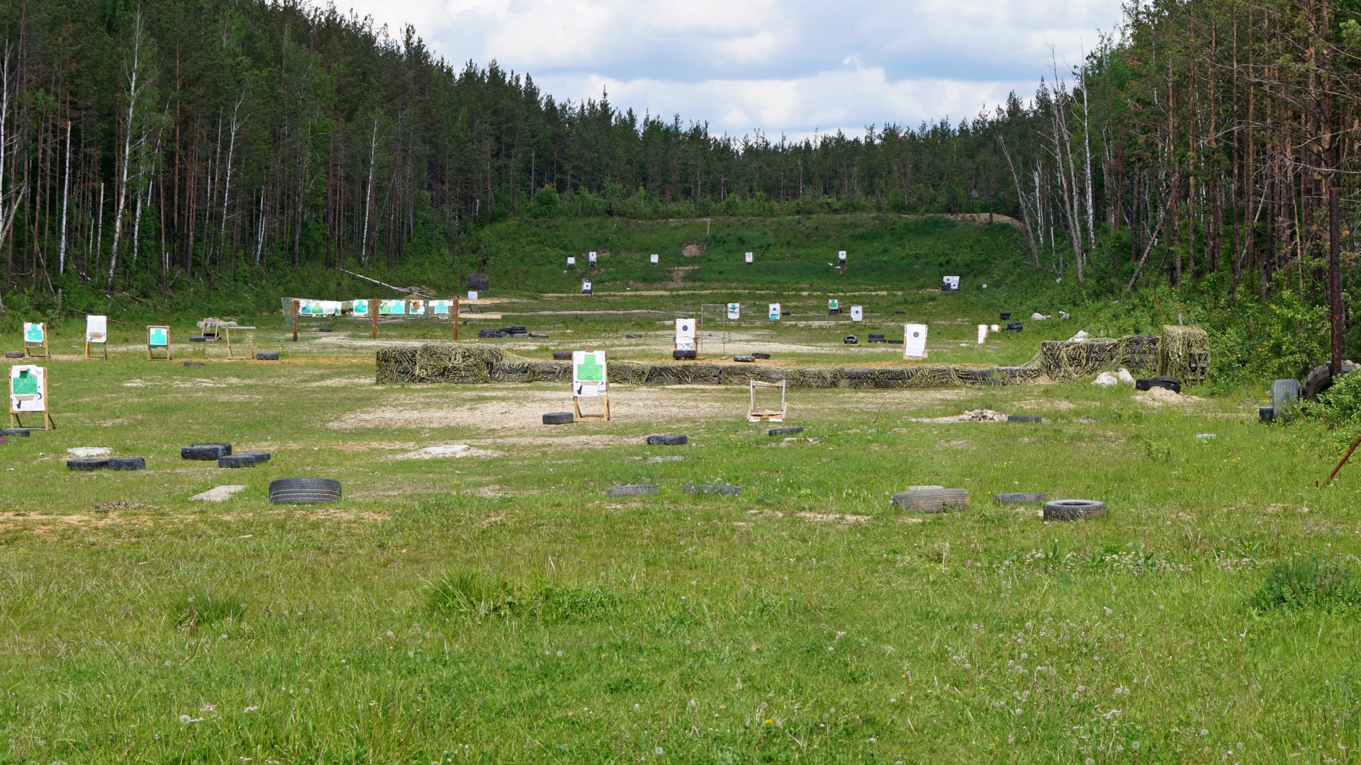 A wide cut shooting range with targets set up in the field. The lane also features layered grass ledges.