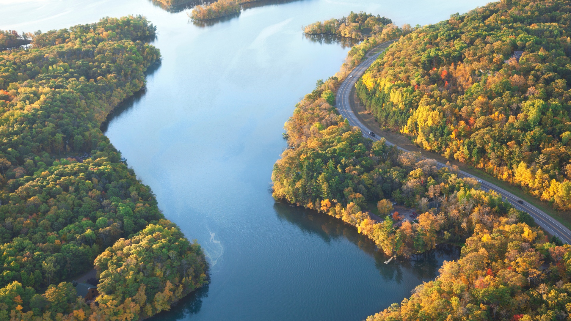 A bird's eye view of the Mississippi River in fall. The forest surrounding the river shows changing leaf colors.