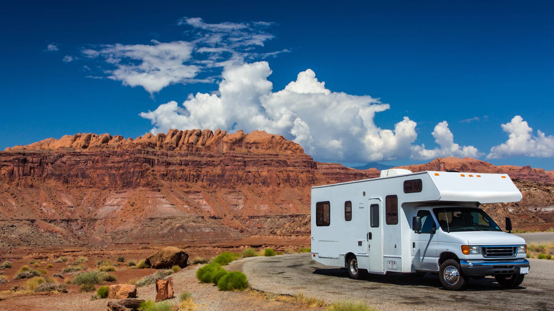 A white recreational vehicle parked on the side of the road in a desert canyon in a southwestern American state.