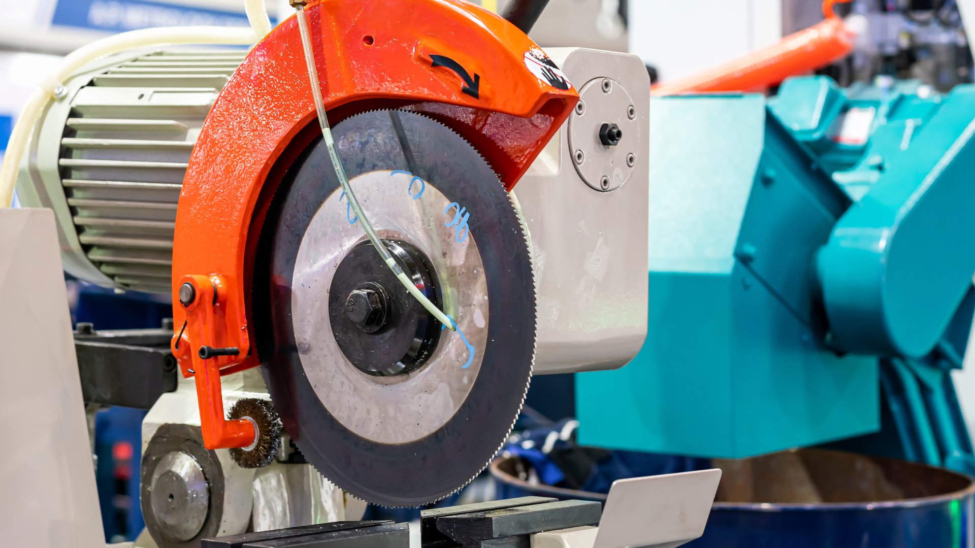 A close up of a cold saw machine sitting in an industrial work facility. It's next to other industrial machines.