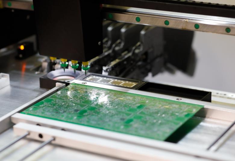 A close-up of a small gantry system with a metal base. Multiple needles attached to the moving head work on a chip.