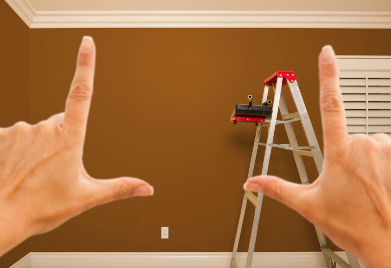 A closeup of two hands framing in the view of a room inside of a home to envision a construction project.