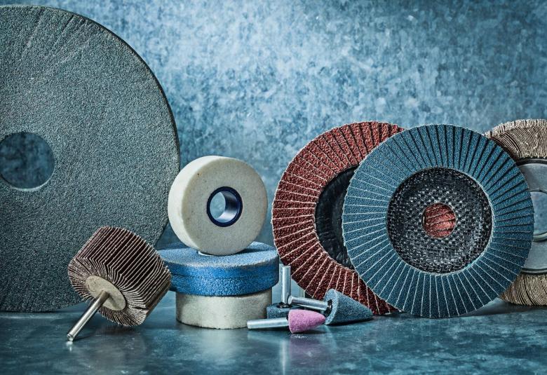 A variety of differently sized and colored grinding wheels and bits set against a natural-stone background.