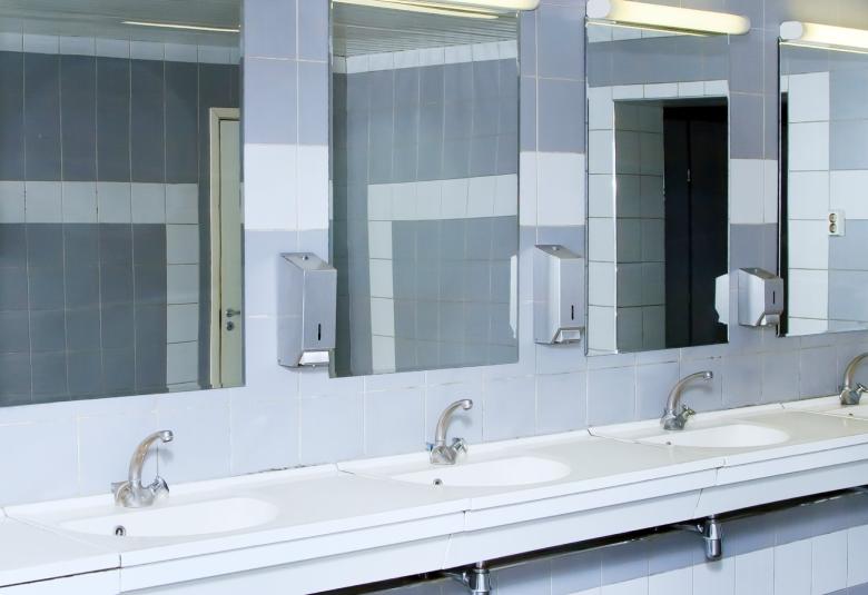 A public bathroom sink area with four sinks. Above each sink are four separated, tall, rectangular mirrors.