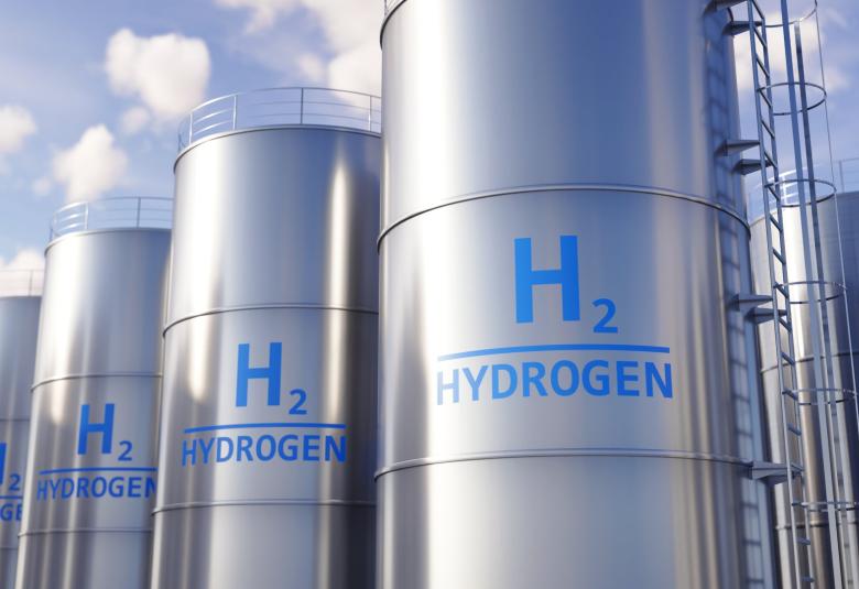 There are multiple tall silver storage tanks with ladders going to the top, each tank labeled "H2 HYDROGEN."