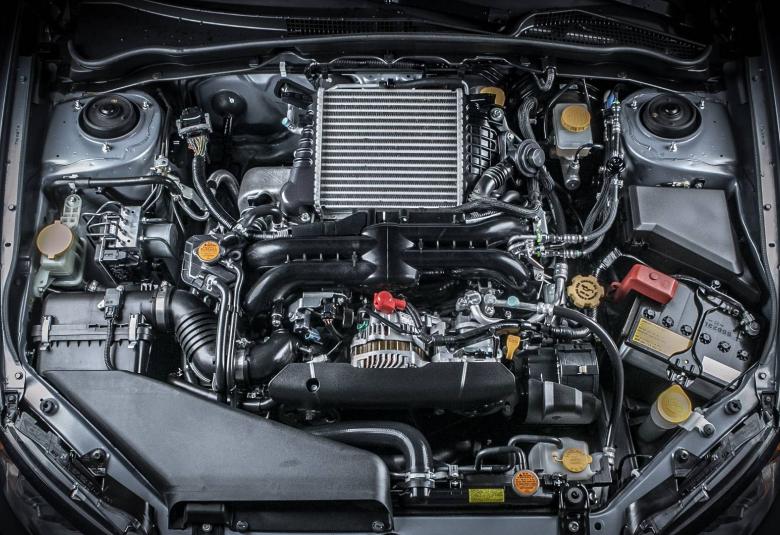 A car has their hood up and there are tons of different components, tubes, and metal parts next to the engine in the middle.